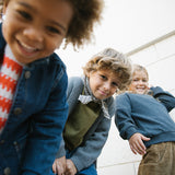 Tre børn iført efterårstøj med strik og denimjakker og tørklæde