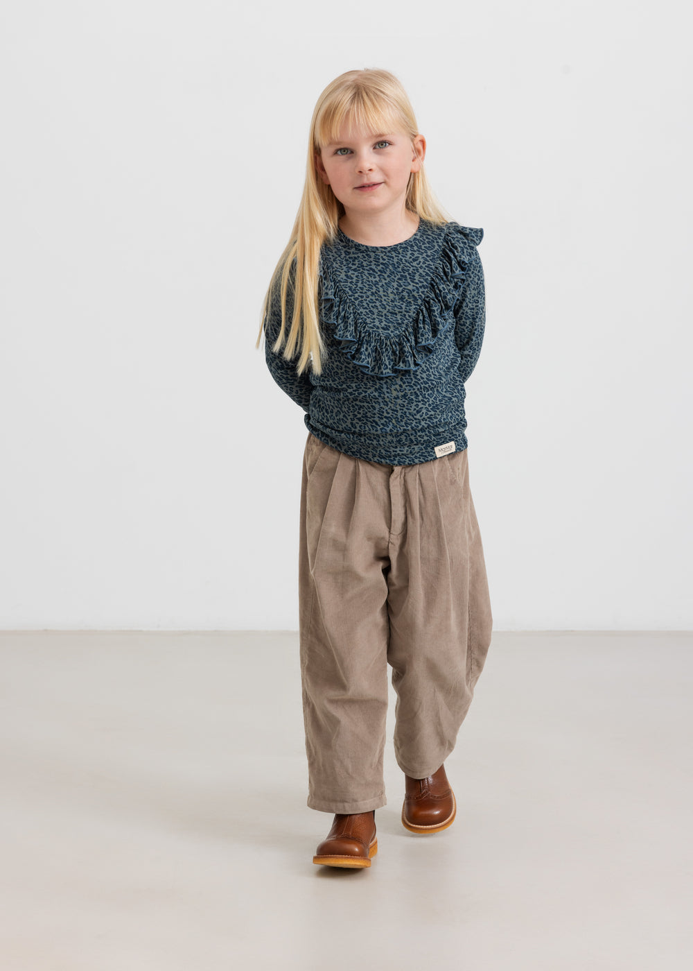 Pige iført beige babyfløjl­sbukser og mørkeblå bluse