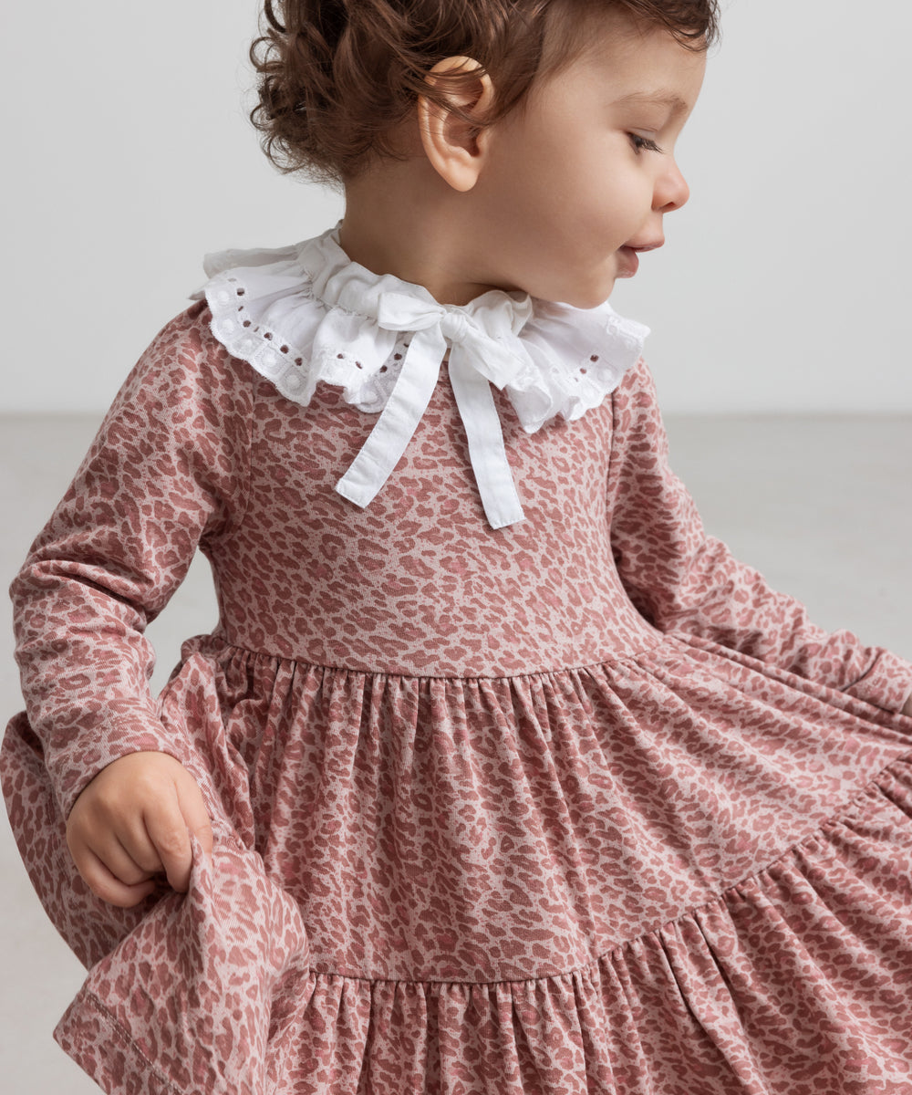 Pige iført lyserød leopardmønstret kjole med hvid krave