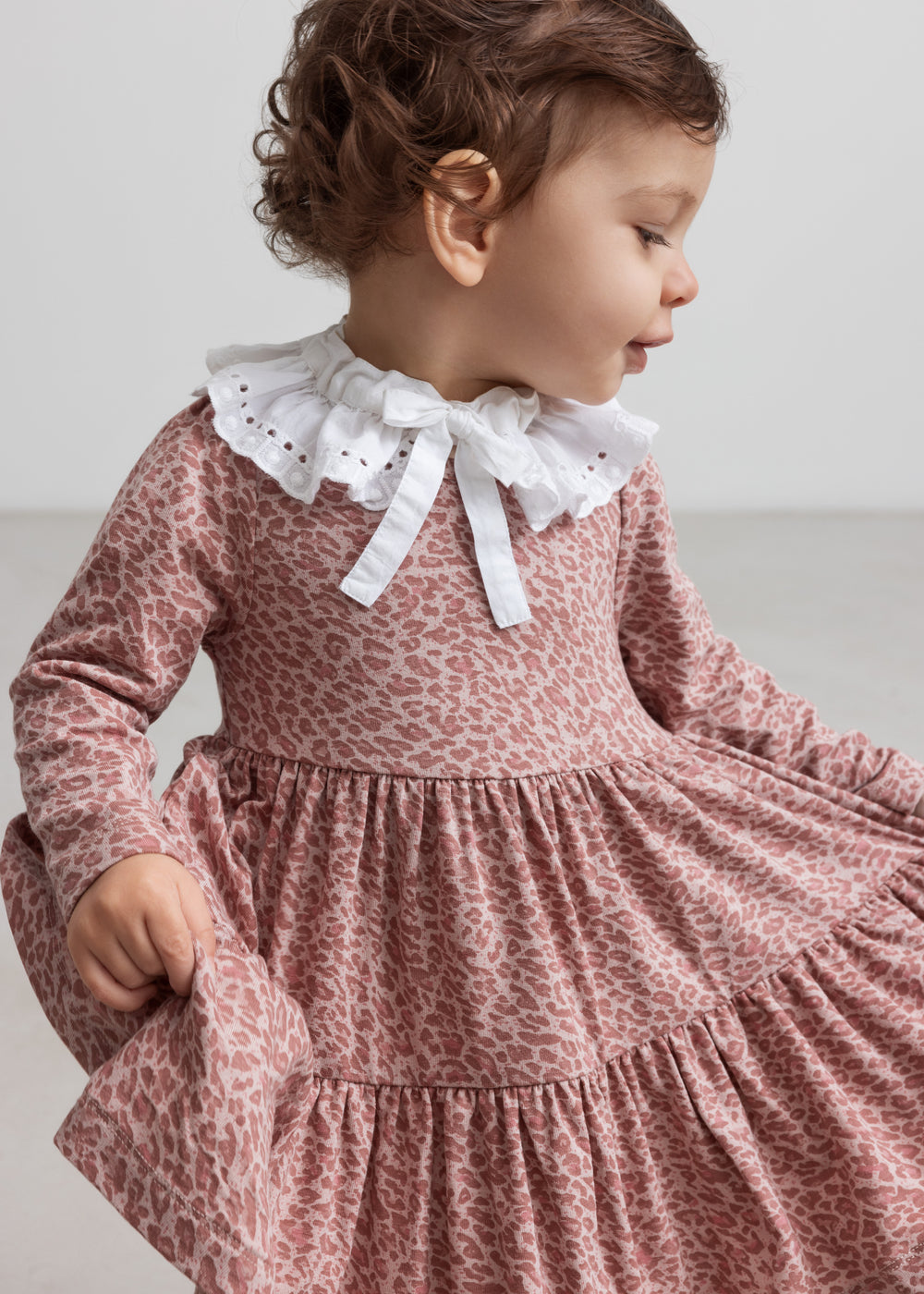 Pige iført lyserød leopardmønstret kjole med hvid krave