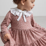 Pige iført lyserød leopardmønstret kjole med hvid krave