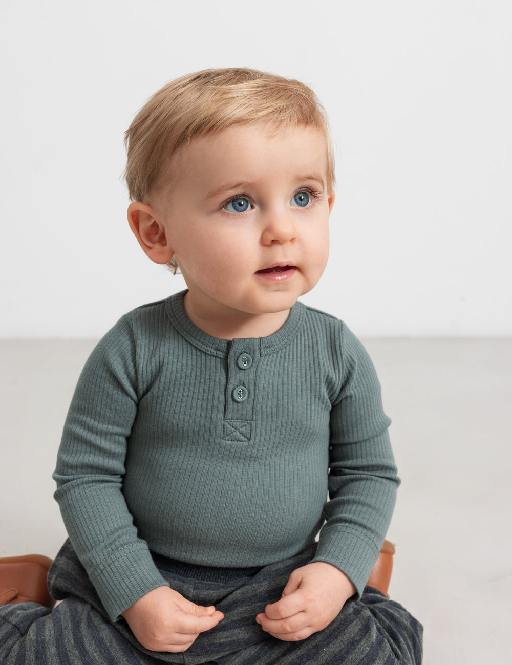 Baby iført grøn ribbody med lange ærmer og knaplukning