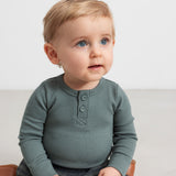 Baby iført grøn ribbody med lange ærmer og knaplukning