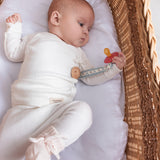 Baby iført hvid pointelle slå-om bluse og bukser liggende i kurv