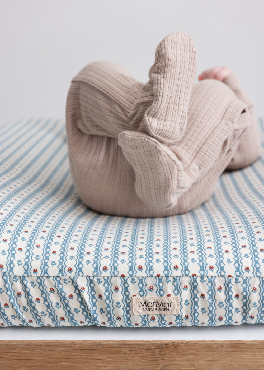 Børn iført beige pointelle heldragt på puslebord