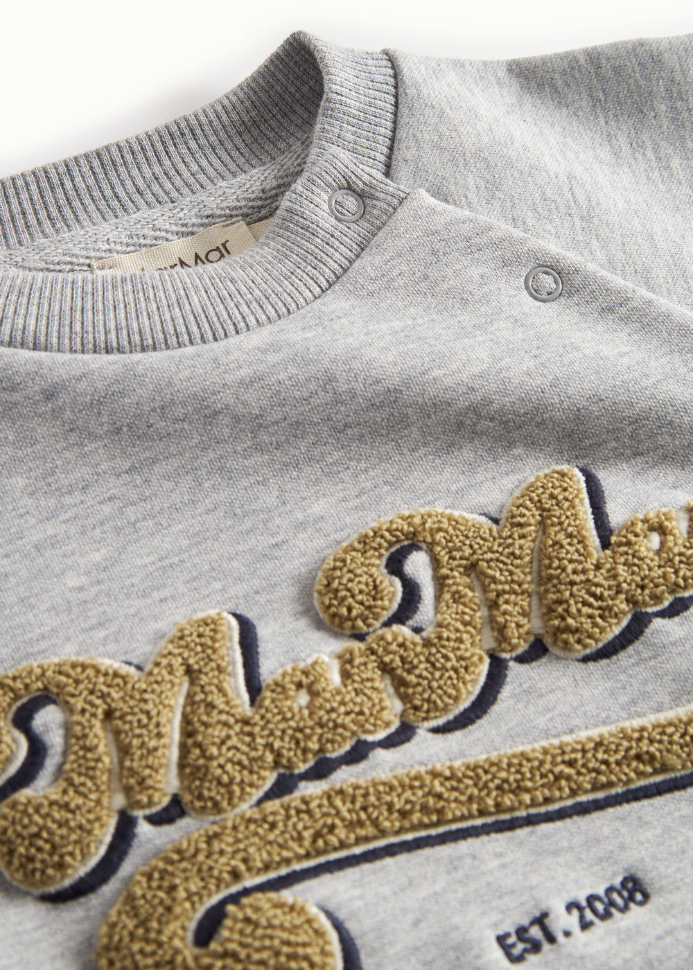 Detalje af guld broderi på grå sweatshirt til børn