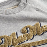 Detalje af guld broderi på grå sweatshirt til børn