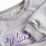 Nærbillede af broderi og ribkant på grå sweatshirt til børn