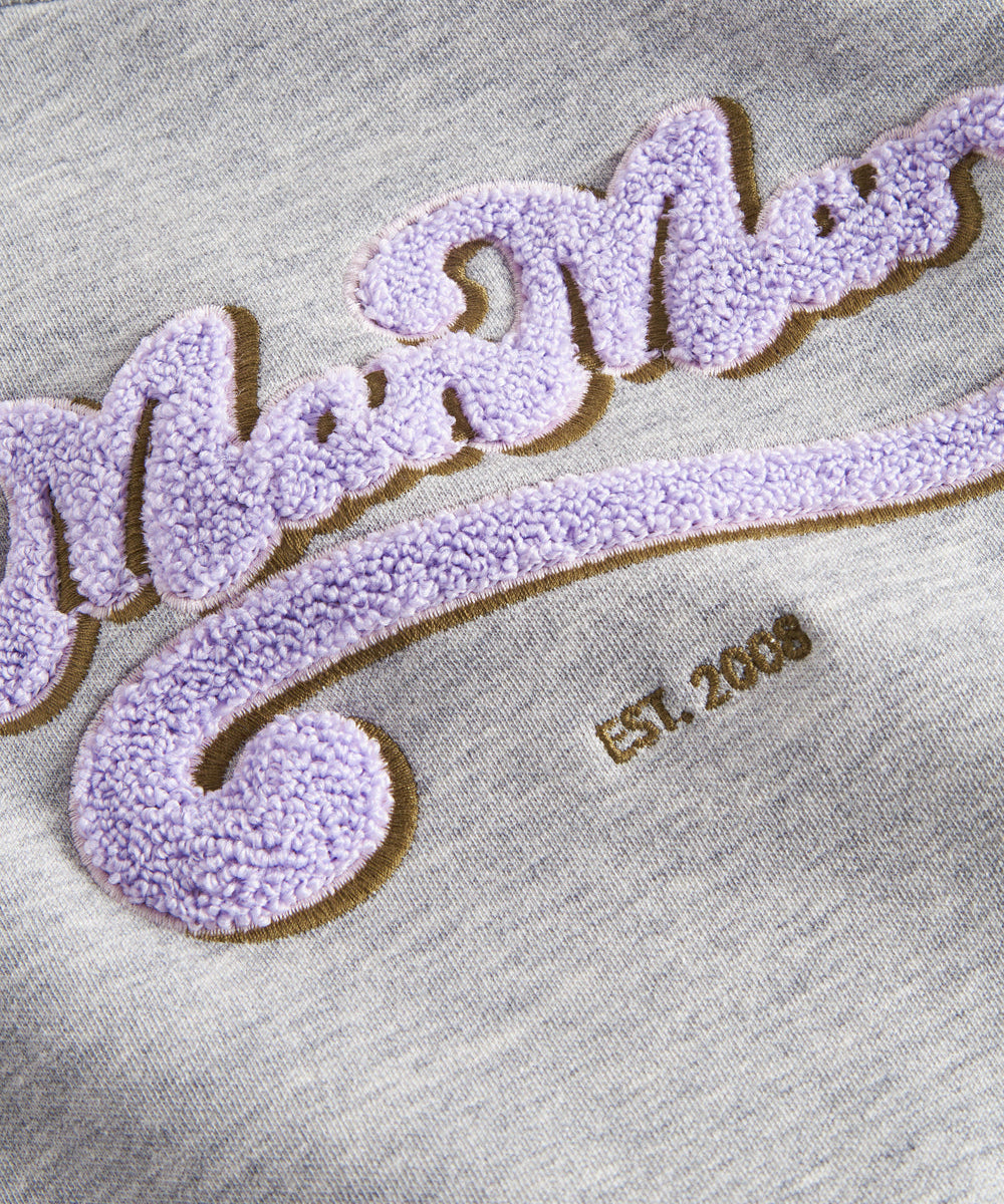 Detalje af lilla og guld broderi på grå sweatshirt til børn