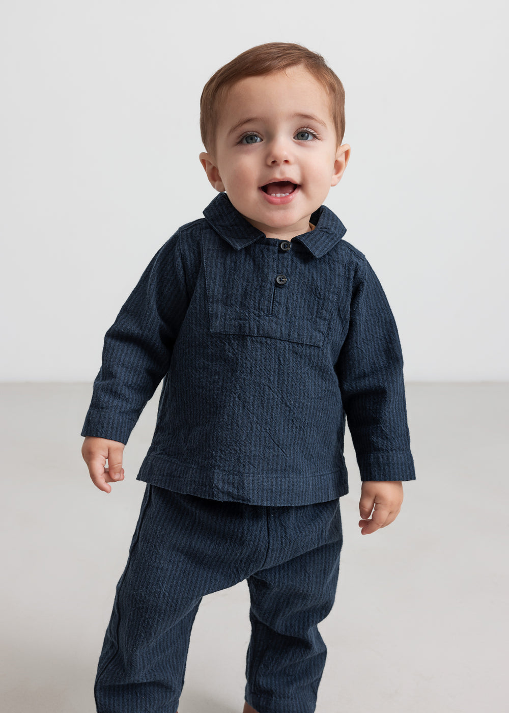 Lille barn iført mørkeblå bukser og matchende skjorte