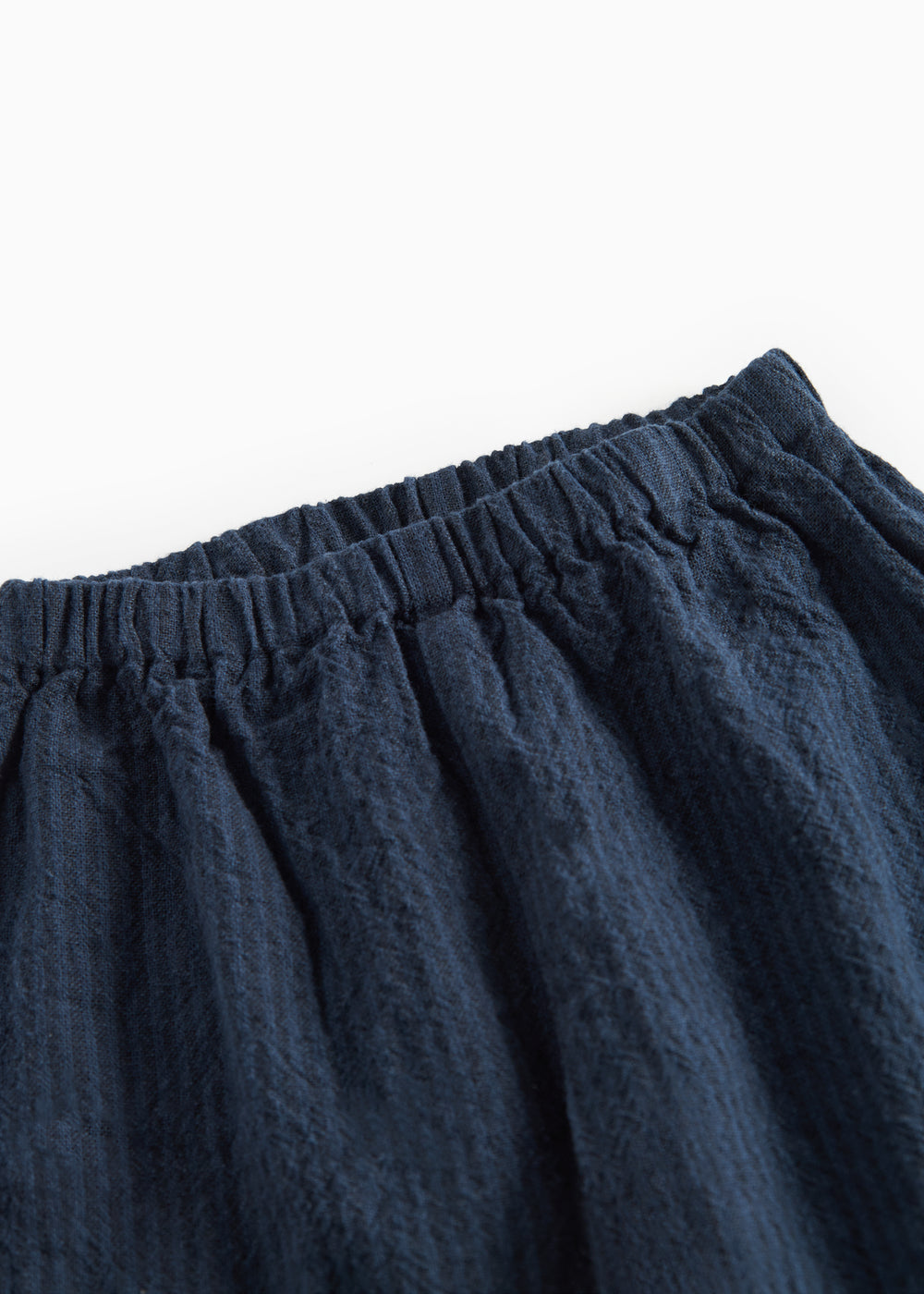 Detaljebillede af elastik i taljen på mørkeblå bukser