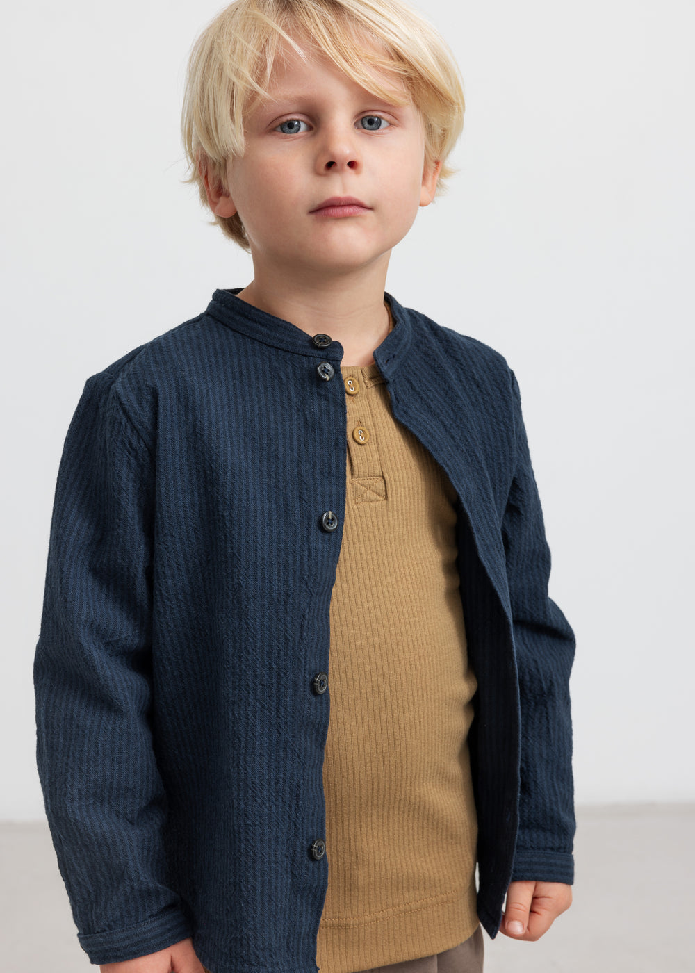 Dreng med blå jakke og brun ribstrikket langærmet t-shirt