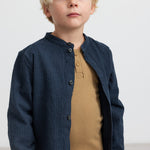 Dreng med blå jakke og brun ribstrikket langærmet t-shirt