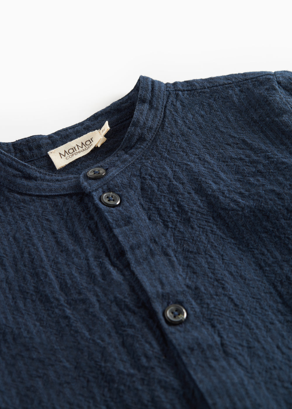 Detaljebillede af knapper og stofstruktur på mørkeblå skjorte