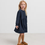 Pige iført mørkeblå kjole med rynket talje 