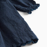 Detaljebillede af ærmekant med bølget afslutning på mørkeblå kjole