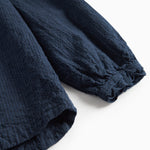 Detaljebillede af mørkeblå bluse med elastik ved ærmekant