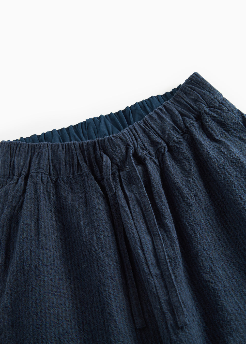 Detaljebillede af mørkeblå damebukser med elastik og let tekstur