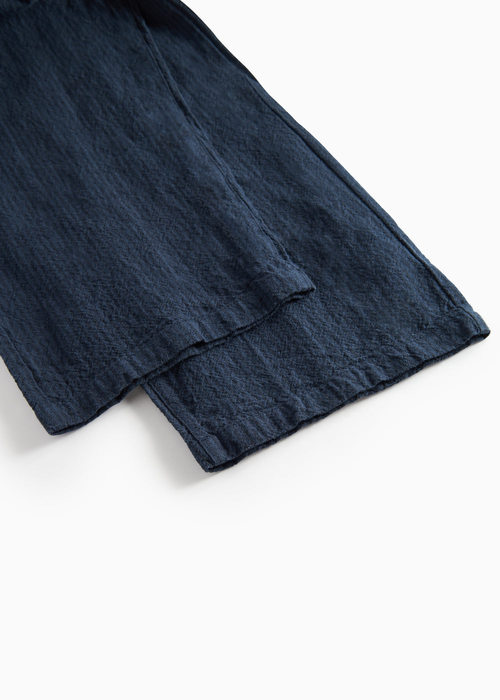 Detaljebillede af mørkeblå damebukser med elastik og let tekstur