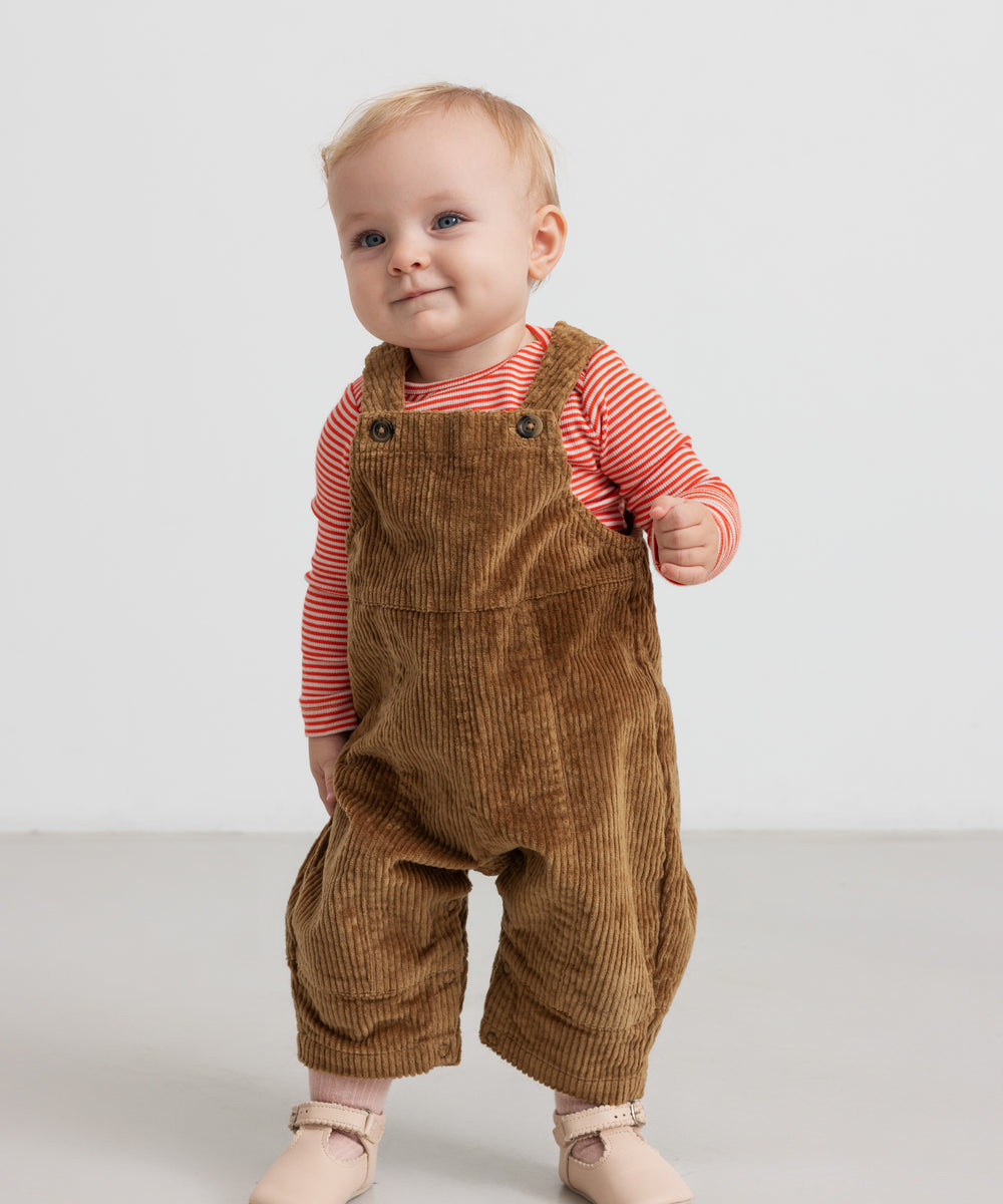 Baby iført rød og hvid stribet body og brune smækbukser