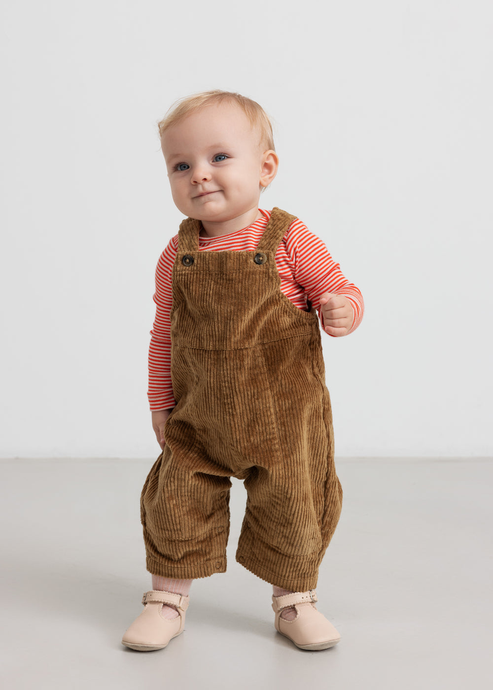 Baby iført rød og hvid stribet body og brune smækbukser