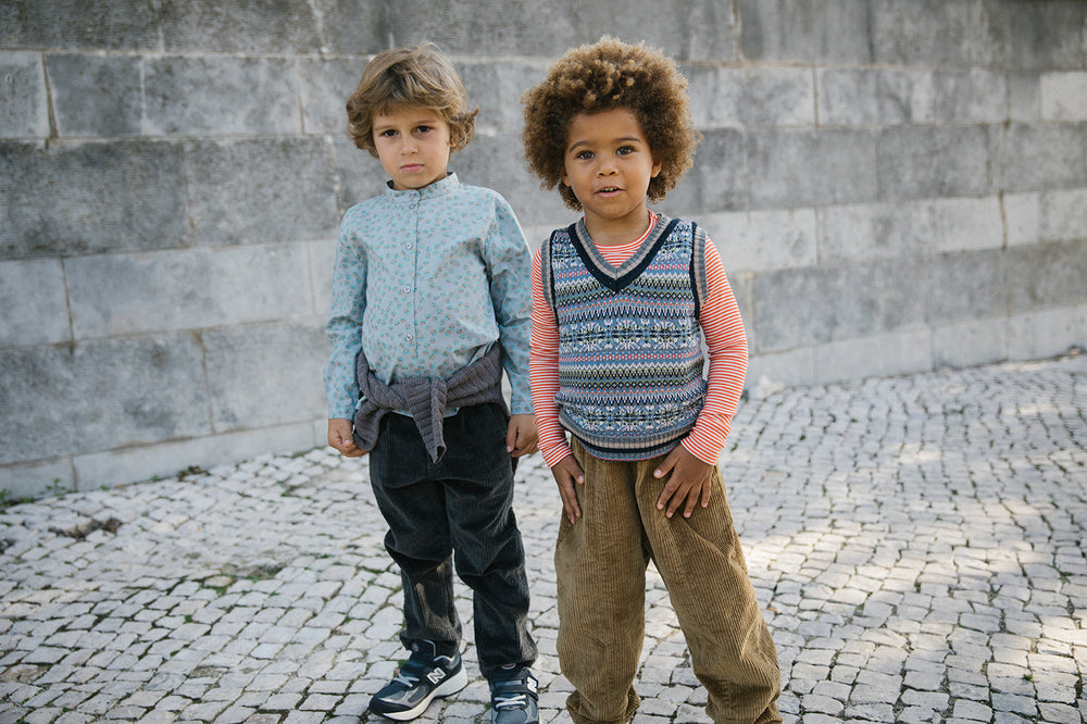 To drenge leger udendørs, den ene iført strikket vest