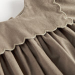 Beige babyfløjlskjole med lange ærmer, bølgekant og lommer til børn