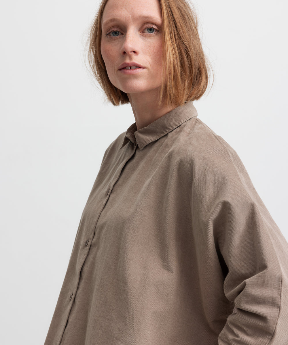 Kvinde iført beige skjorte med kinakrave