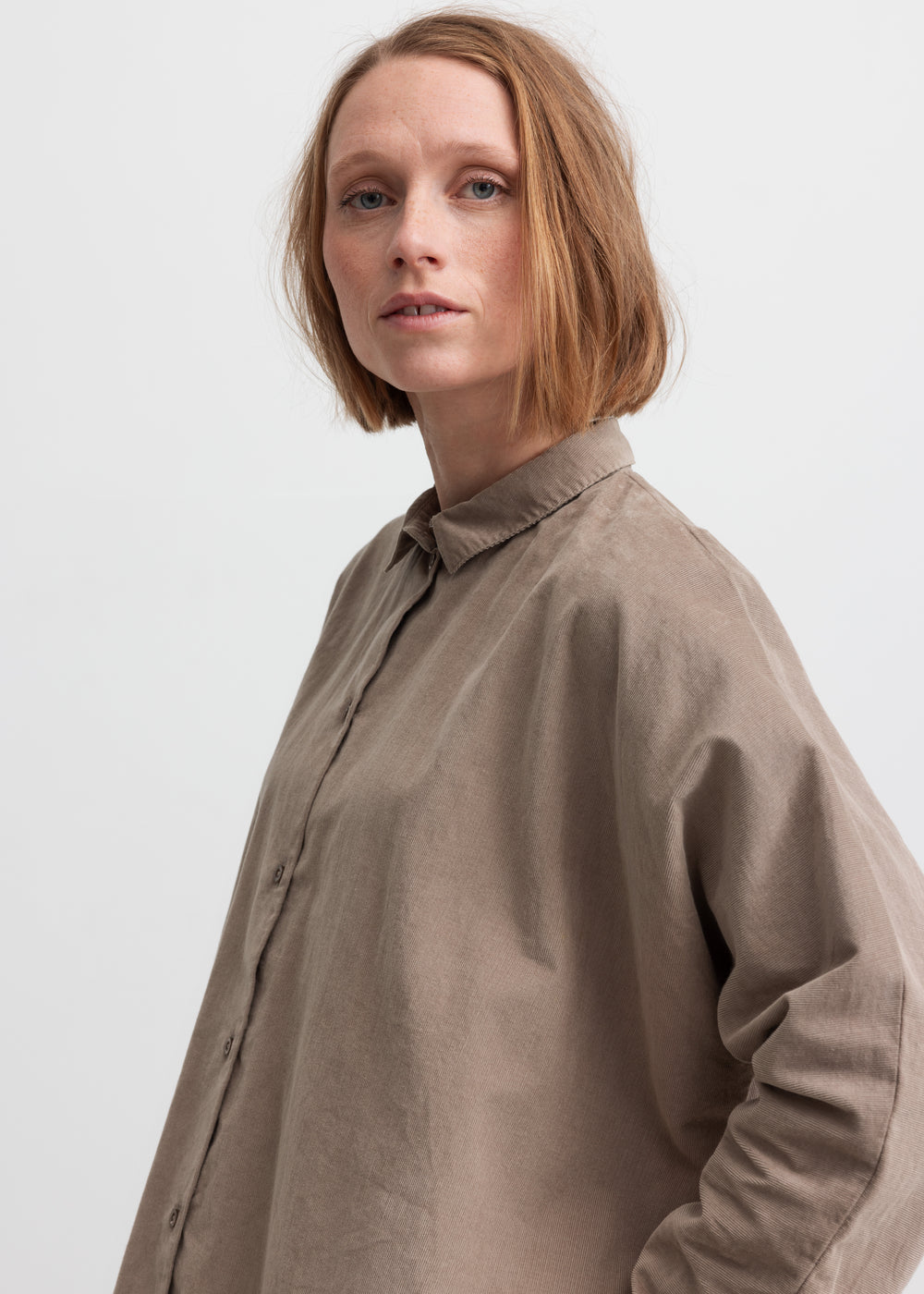 Kvinde iført beige skjorte med kinakrave