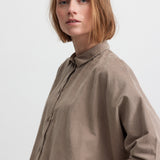 Kvinde iført beige skjorte med kinakrave