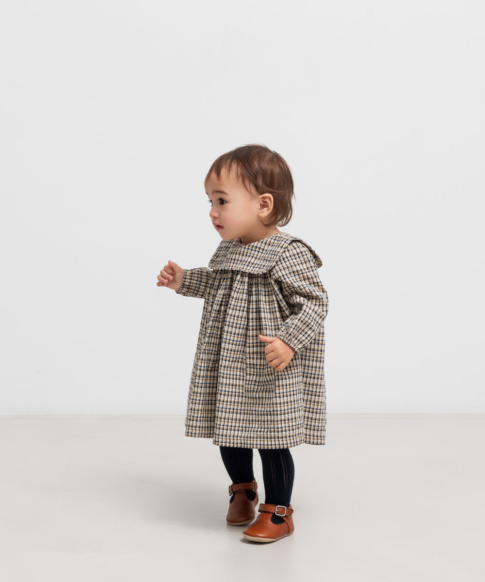 Lille børn iført brun ternet kjole i crepet bomuld