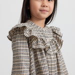 Pige iført brun ternet strikkjole med flæser foran