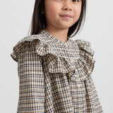 Pige iført brun ternet strikkjole med flæser foran