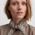 Kvinde i beige skjorte med ternet tørklæde om halsen