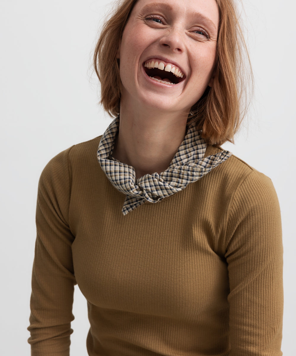 Kvinde iført brun ternet tørklæde bundet om halsen