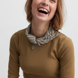 Glad kvinde iført langærmet brun ribstrikket t-shirt 