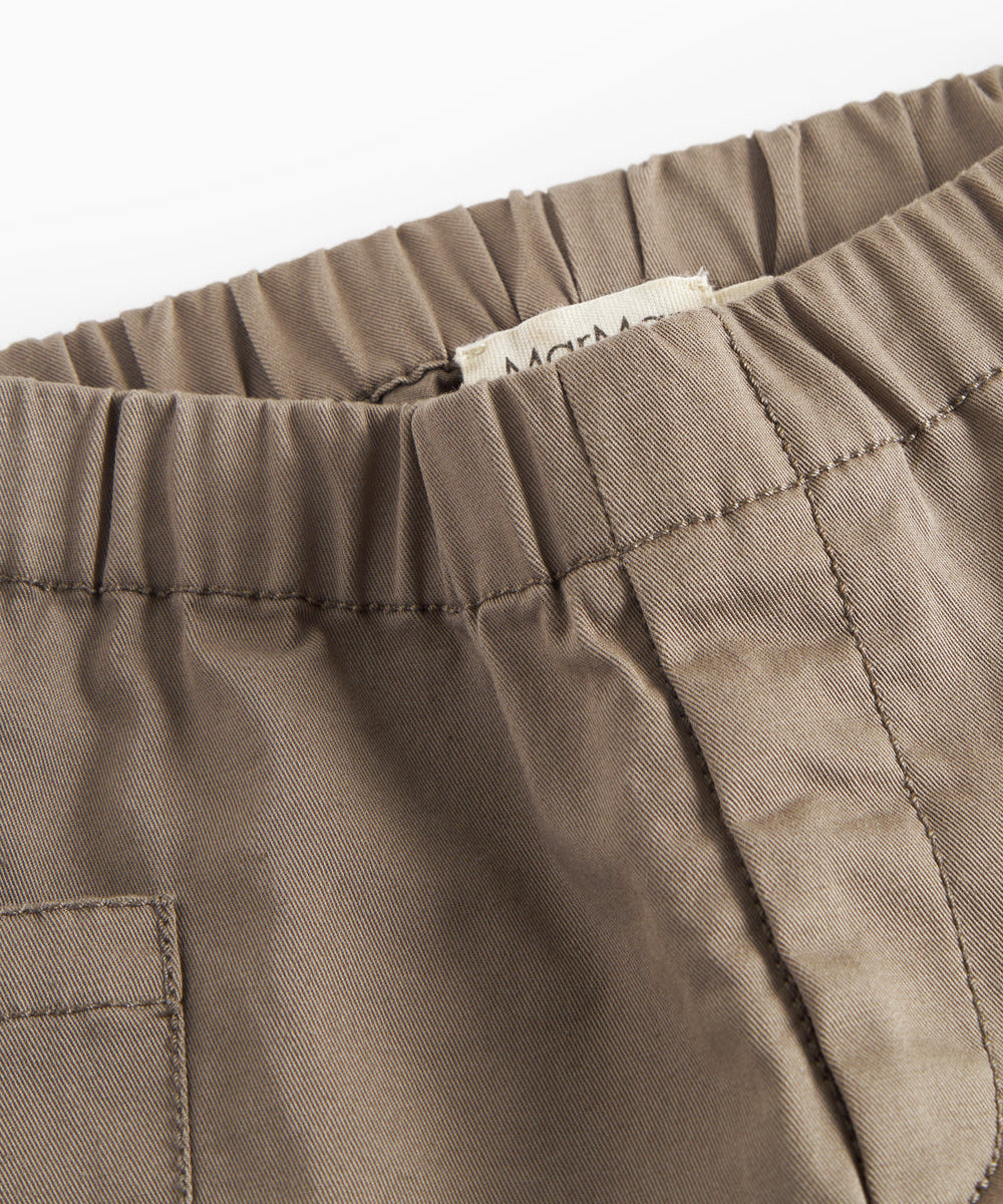 Nærbillede af khaki bukser med synlige sømme og elastik i taljen