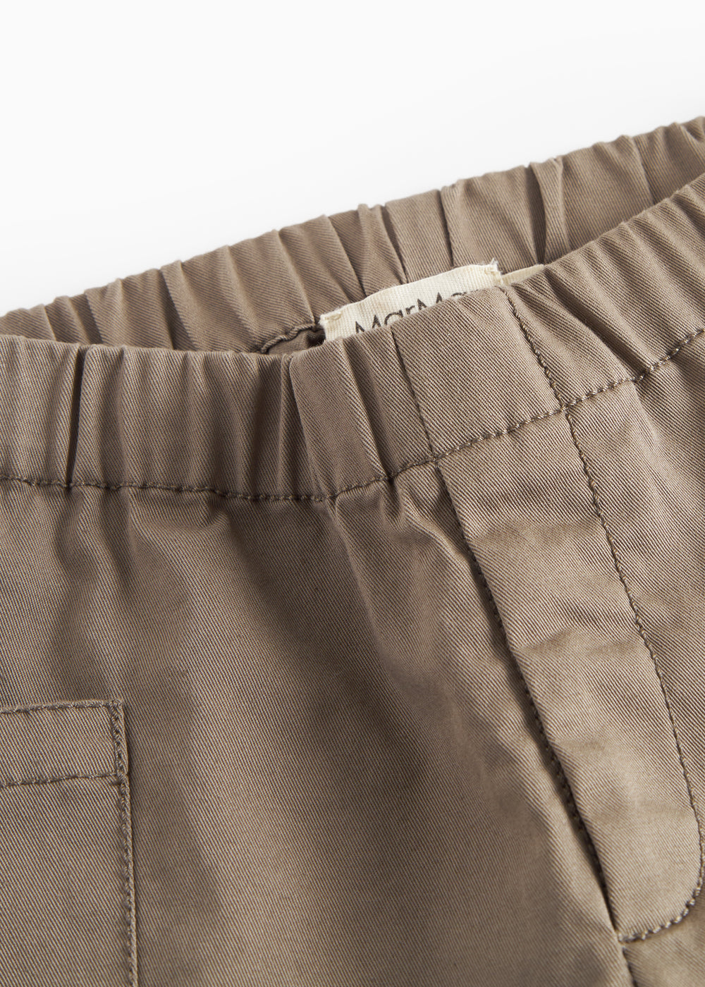 Nærbillede af khaki bukser med synlige sømme og elastik i taljen