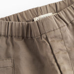 Nærbillede af khaki bukser med synlige sømme og elastik i taljen