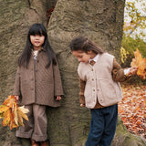 Børn ved træ med efterårsløv, iført bukser og jakker