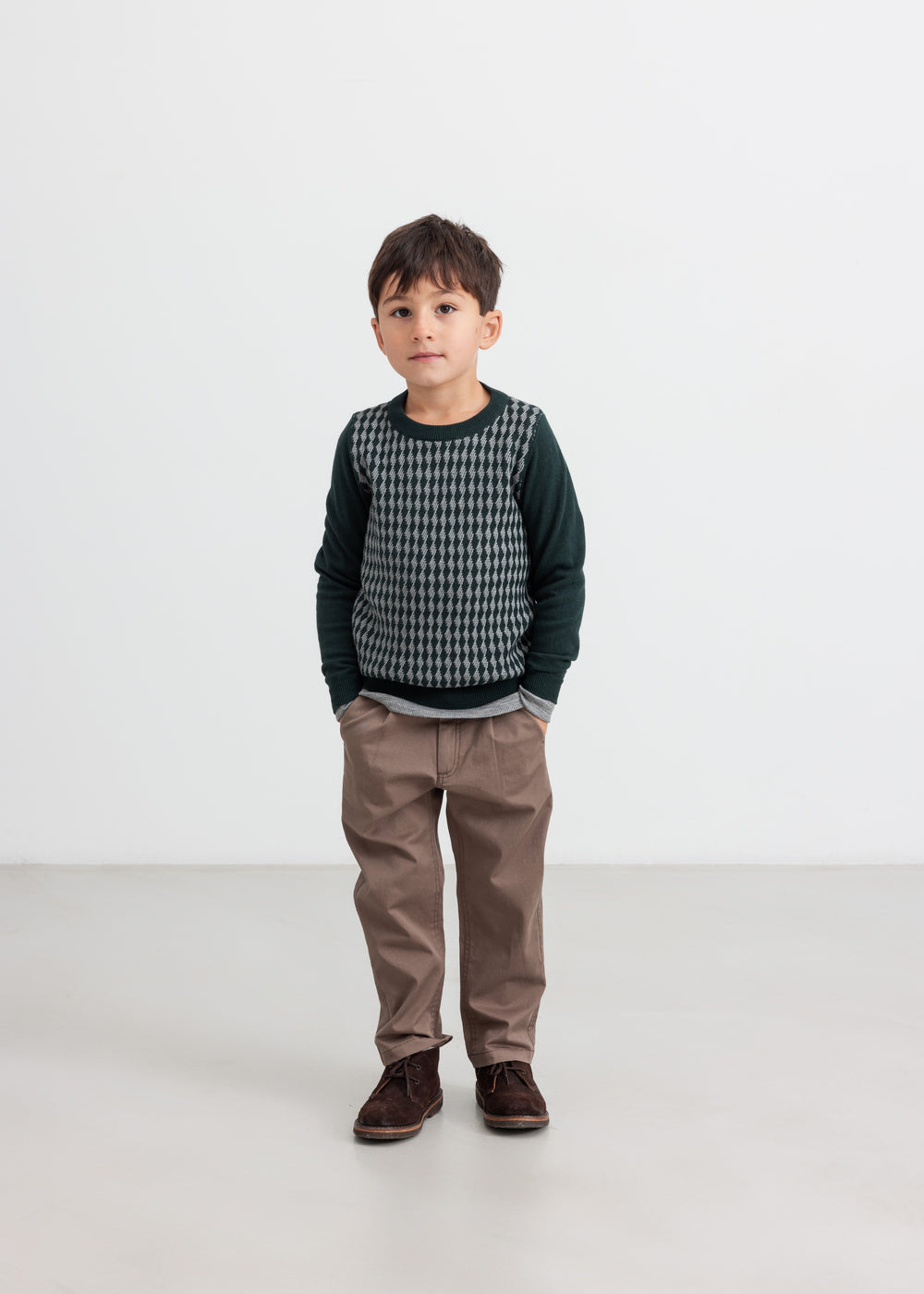 Dreng iført mørkegrøn strikket bluse med ternet mønster og brune bukser til børn
