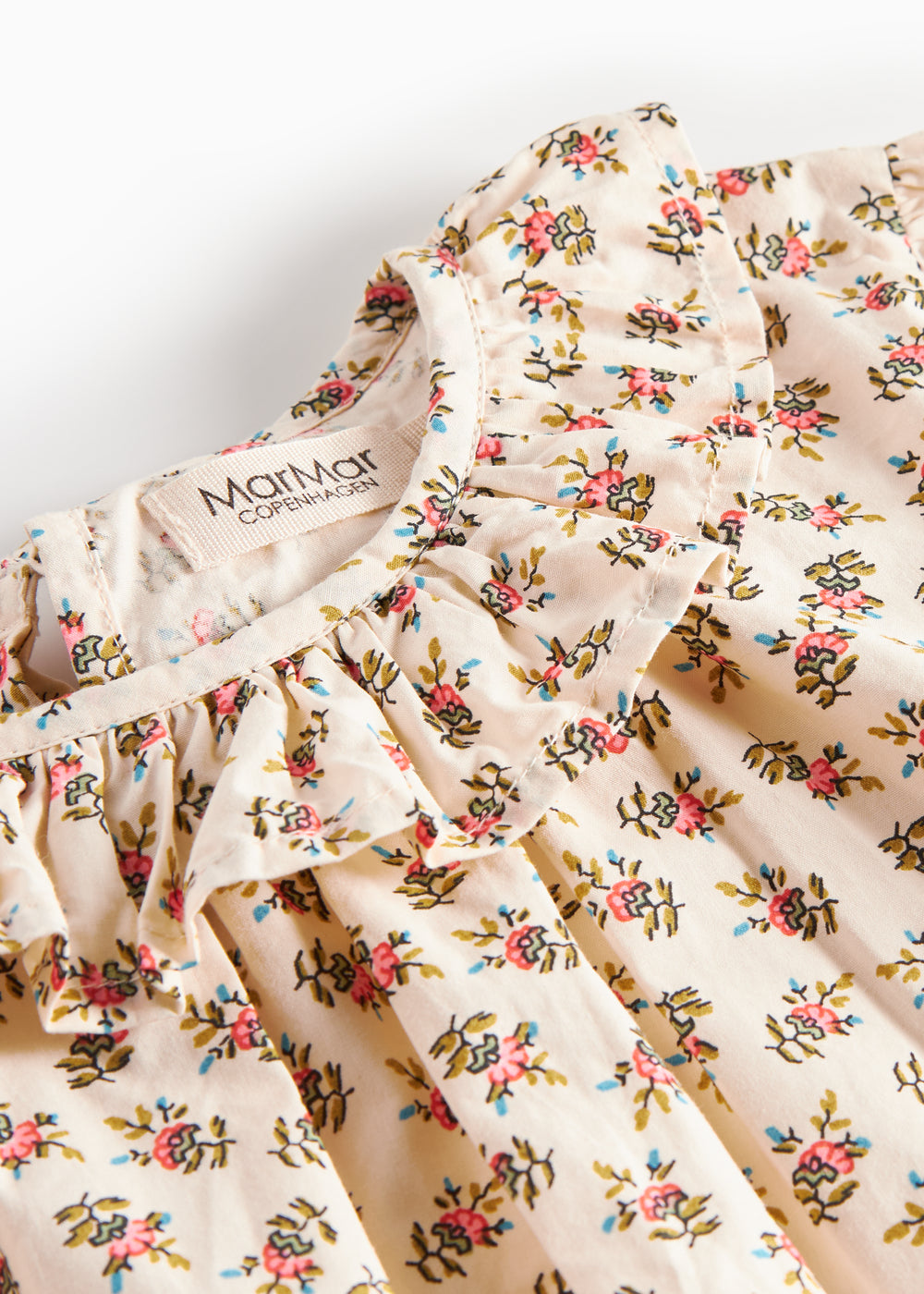 Detaljebillede af bluse med blomstermønster og flæsedetalje