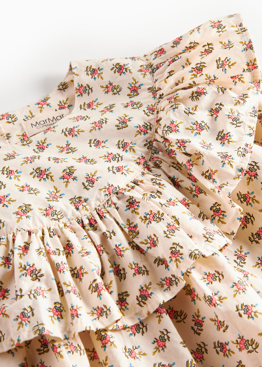 Detaljebillede af flæseærme og blomsterprint på kjole