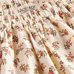 Nærbillede af stof med blomstermønster og flæsekant på nederdel