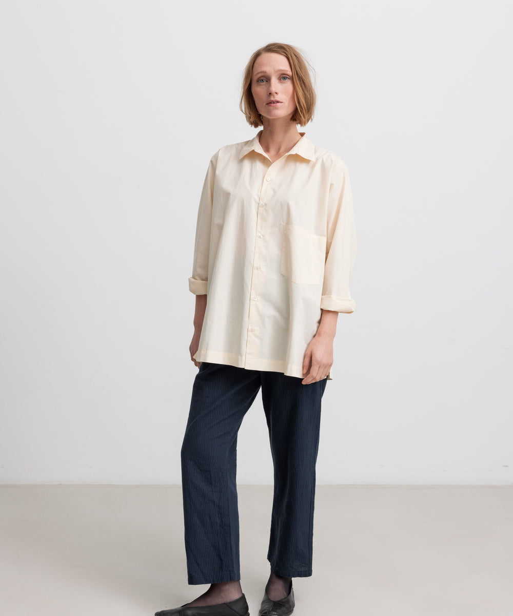 Kvinde iført cremefarvet bluse med lange ærmer og klassisk krave