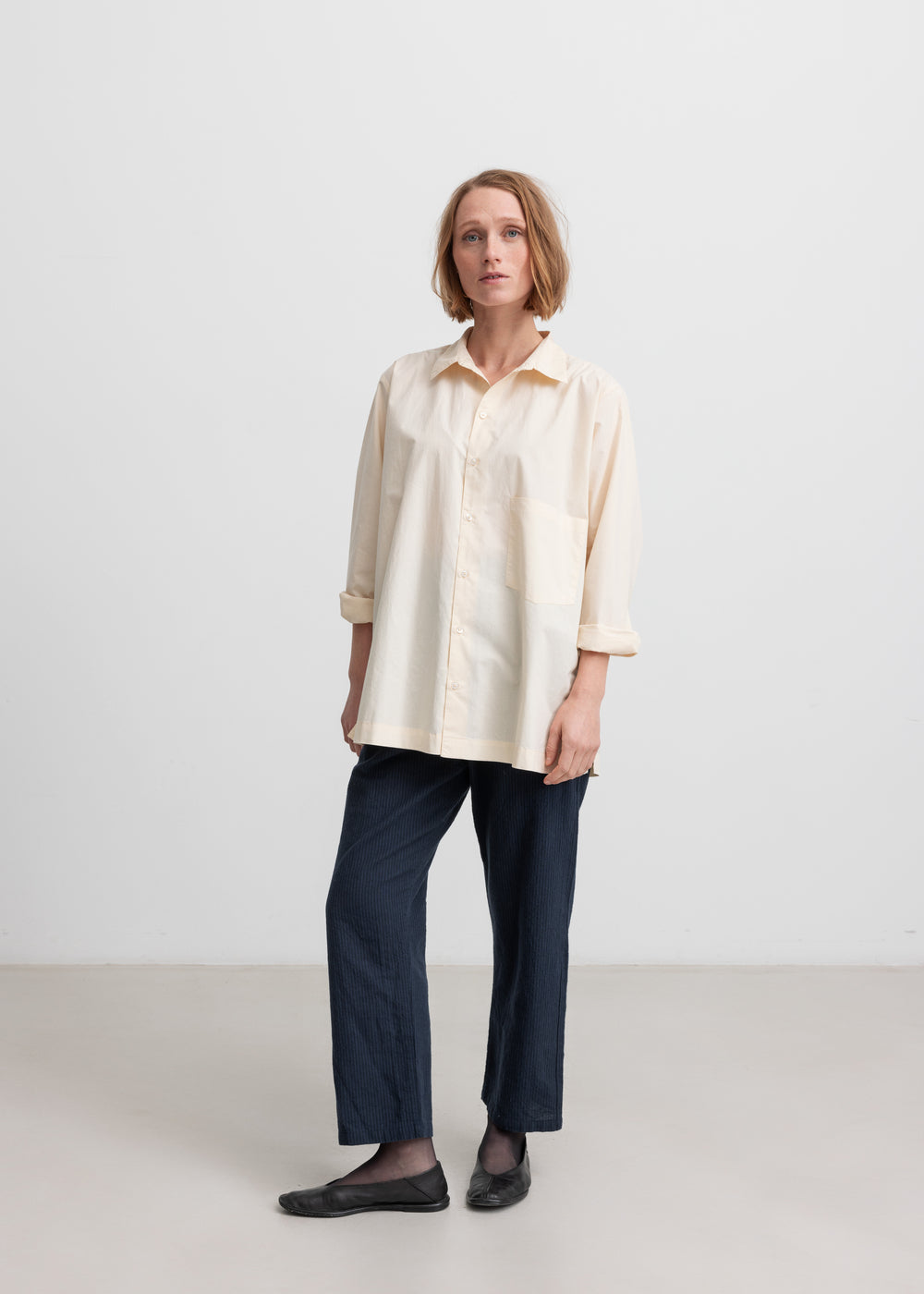 Kvinde iført mørkeblå bukser og beige skjorte