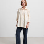 Kvinde iført mørkeblå bukser og beige skjorte