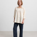 Kvinde iført mørkeblå bukser og beige skjorte