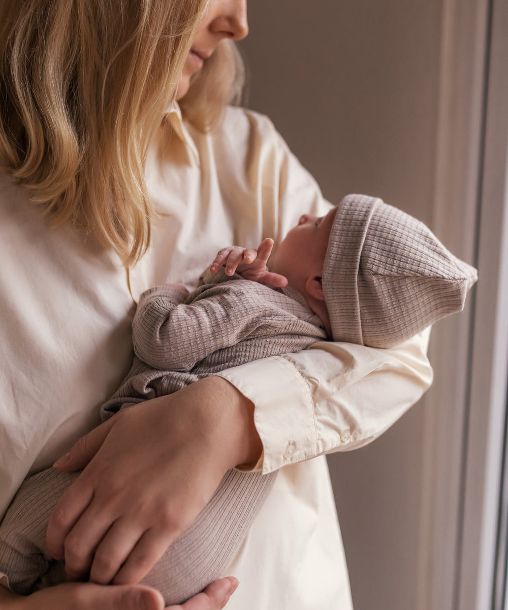 Kvinde holder baby iført cremefarvet bluse