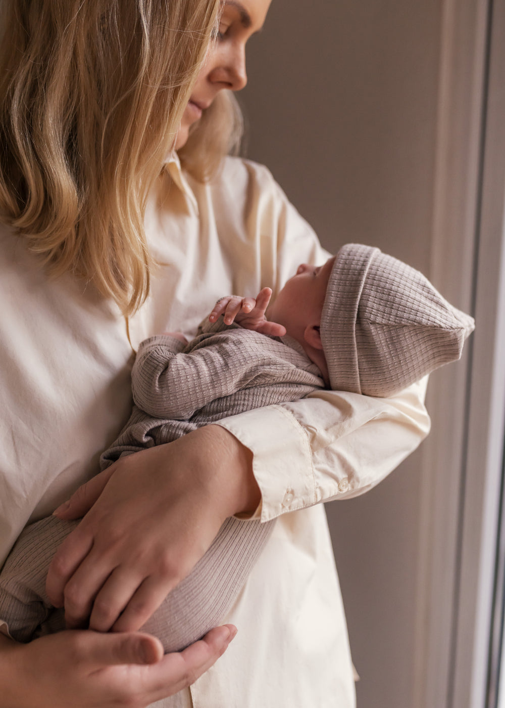Kvinde holder baby iført cremefarvet bluse